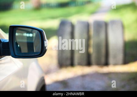 Seitenspiegel des Fahrzeugs gegen vier Reifen, saisonales Rad- und Reifenwechselkonzept Stockfoto