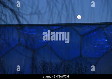 Peking, China. 15th. Februar 2022. Das am 15. Februar 2022 aufgenommene Foto zeigt den Mond und das Nationale Wassersportzentrum in Peking, der Hauptstadt Chinas, am 15. Februar 2022. Quelle: Huang Xiaobang/Xinhua/Alamy Live News Stockfoto