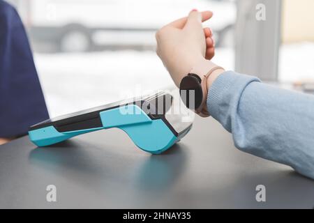 Kunden, die drahtlos oder kontaktlos mit der Smartwatch bezahlen. Store Worker akzeptieren Zahlungen über nfc-Technologie.geringe Schärfentiefe Stockfoto