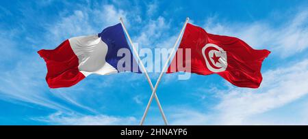 Gekreuzte Nationalflaggen von Frankreich und Tunesien, die im Wind bei bewölktem Himmel winken. Symbolisiert Beziehung, Dialog, Reisen zwischen zwei Ländern Stockfoto