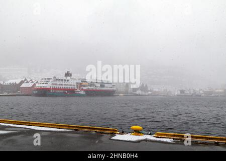 Schneesturm in Bergen. Auto- und Passagierfähre Trollfjord am Bryggen Kai, im Hafen von Bergen, Norwegen. Bunkertanker Bergen Tank liefert Stockfoto