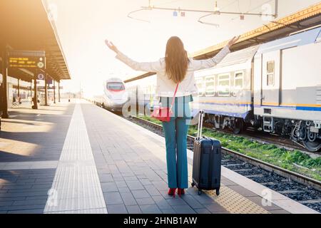 Geschäftsfrau mit Trolley-Tasche verlor den Zug, weil sie spät am Bahnsteig ankam - wunderschönes Mädchen, das die Hände winkte, zerstreuten sich Stockfoto