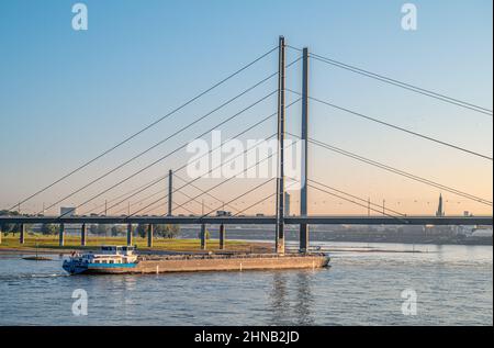 Binnenschiff vor der Düsseldorfer Rheinkniebrücke im Morgengrauen, NRW, Deutschland Stockfoto