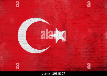 Vollformatfoto einer verwitterten Flagge der Türkei, gemalt auf einer verputzten Ziegelwand. Stockfoto