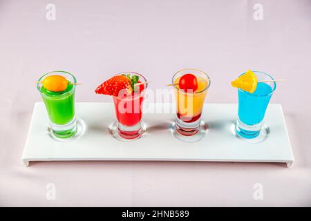 Verschiedene bunte grün blau gelb rot und weiß schöne Alkohol süß Schützen Schüsse Cocktail frisches Getränk in kleinen Gläsern. Alkoholische Tropica Stockfoto