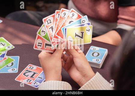 Junger Mann, der Brettspielkarten bequem von zu Hause hält Stockfoto