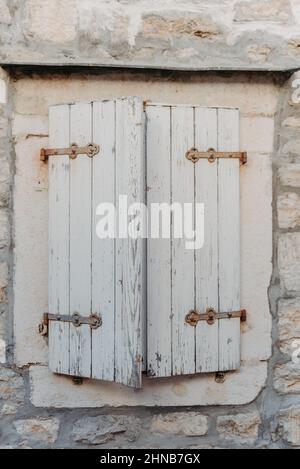 Altes Fenster mit hölzernen Fensterläden auf gelber Stuckwand und Kopierraum Alte Fensterläden mit Blumen. Montenegro. Mittelmeer. Ein altes Fenster in Einem Stockfoto
