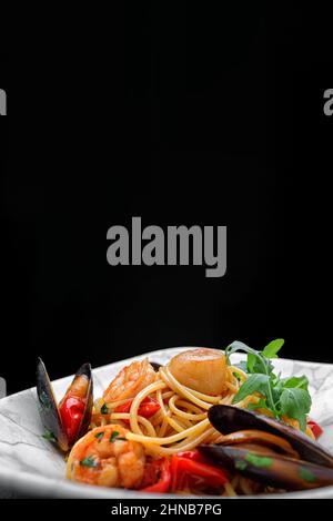 Spaghetti mit Meeresfrüchten, Jakobsmuscheln, Garnelen, Muscheln auf einem dunklen Hintergrund mit Platz für Text Stockfoto