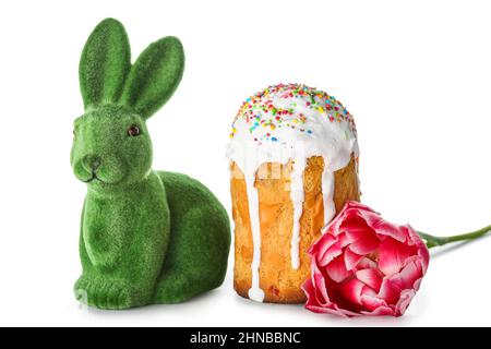 Niedlicher Osterhase mit Kuchen und Blume auf weißem Hintergrund Stockfoto