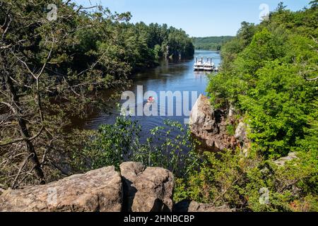 Fischerboot, das den St Croix River und die Taylors Falls Queen and Princess am Dock auf dem Dalles of the St. Croix im Interstate St. Park hinauffährt. Stockfoto