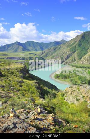 Steinpyramiden am Ufer des smaragdgrünen Flusses inmitten der felsigen Berge unter dem blauen Himmel. Sibirien, Russland Stockfoto