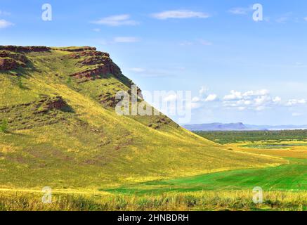 Felsige Klippen in der Steppe im Sommer unter einem blau bewölkten Himmel. Sibirien, Russland Stockfoto