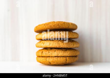 Haufen Haferflocken auf weißem Holztisch auf hellem Wandhintergrund Stockfoto