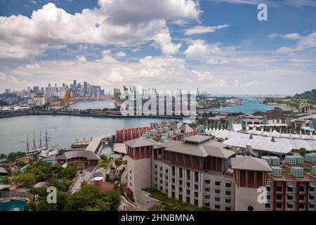 Der riesige verkehrsreichste Logistikhafen in Singapur, viele Kräne zum Transport von Containern, riesige Frachtschiffe im Hintergrund, Einkaufszentren und Wolkenkratzer Stockfoto