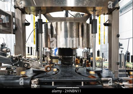 Die automatische Ausrüstung bringt Verschlüsse auf Flaschen mit alkoholischen Getränken Stockfoto