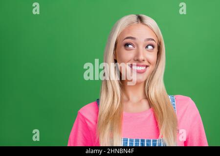 Foto von niedlichen schönen positiven Dame suchen leeren Raum glänzend Lächeln tragen gestreiften insgesamt isoliert grüne Farbe Hintergrund Stockfoto