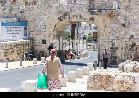 Eine Frau mit einer Tasche nähert sich den historischen Mauern der Altstadt von Jerusalem an der Batei Mahase Street am Dung Gate, auch bekannt als Silwan oder Mughrabi Gate. Stockfoto