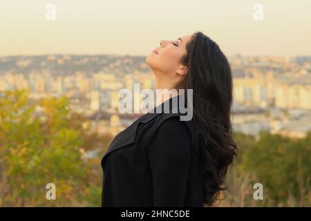 Attraktive rumänische Frau in dunklem Freizeitkleid gegen die Stadt Rumänien während der goldenen Stunde Stockfoto