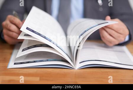 Auf dem Laufenden zu bleiben ist der Schlüssel zum Erfolg. Ausgeschnittene Aufnahme eines nicht identifizierbaren Mannes, der ein Buch liest. Stockfoto