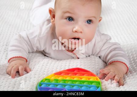 Happy Kid spielt mit Pop IT. Neugeborenes Baby spielt mit einfachen Dimple. T Stockfoto