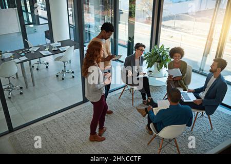 Stärkung von Partnerschaften durch Teamarbeit. Aufnahme einer Gruppe von Kreativen, die sich in einem modernen Büro treffen. Stockfoto