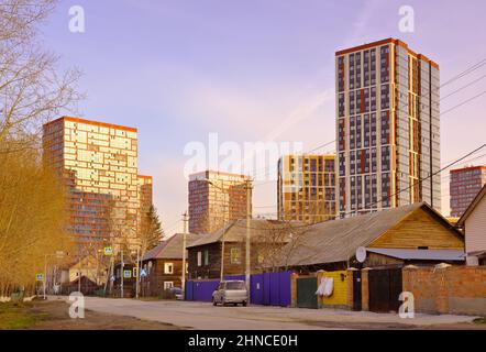 Nowosibirsk, Sibirien, Russland-05.03.2021: Neues Wohngebiet Clear Coast. Hohe moderne Gebäude stehen über den alten Holzgebäuden gegenüber Stockfoto