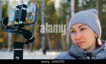 Frau, die auf einem Handheld-Film hält 3-Achsen-Gimbal-Stabilisiergerät im Winter für Smartphone. Girl Blogger Make Selfie, Broadcast Video Blogging, Vlogging. Videograf Operator Nimmt Fotovideo Auf. Stockfoto