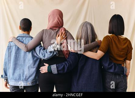 Rückansicht von vier Frauen mit umschrappten Armen zur Unterstützung des Internationalen Frauentags Stockfoto