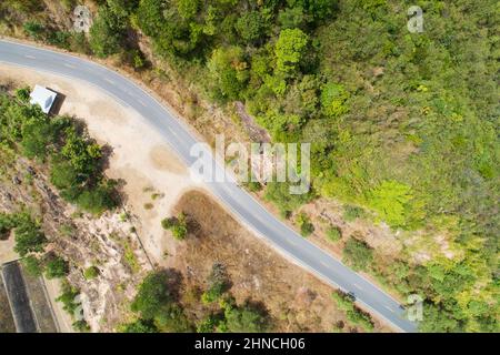 Reisen Sie auf hügeliger Straße im Frühjahr Luftaufnahme Straßenkurvenkonstruktion bis zum Berg erstaunlich von oben nach unten Bild von Drohne Kamera Stockfoto