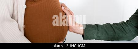 Beschnittene Ansicht des afroamerikanischen Mannes, der den Bauch der Schwangeren berührt, Banner Stockfoto