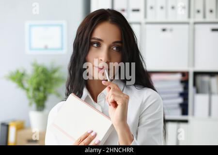 Frau mit silbernem Stift auf dem Mund und denkt über neue Ideen nach Stockfoto