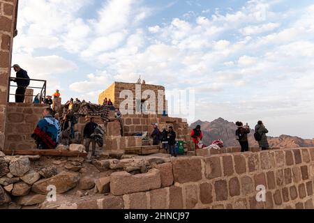 Touristen stehen am Rande einer Klippe und beobachten den Sonnenaufgang. Trekking zum Mount Moses. Sinai-Halbinsel, Ägypten. 14. Oktober 2022. Stockfoto