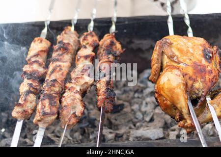 Eine Frauenhand in einem Fäustling fritiert an einem sonnigen Wintertag einen Grill auf dem Grill in der Natur. Selektiver Fokus. Nahaufnahme Stockfoto