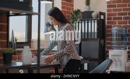 Frau wird gefeuert und packt Habseligkeiten vom Schreibtisch. Unternehmer sammeln Dinge nach der Entlassung aus dem Startup-Geschäft Job. Frustrierte Person, die das Unternehmen verlässt. Stockfoto