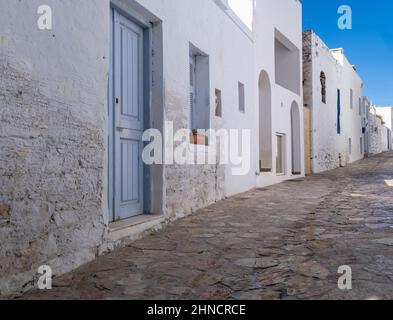 Griechenland, Insel Ano Koufonisi. Neues und gealtertes traditionelles Steingebäude, in weiß-blauer Kykladen-Architektur. Leere Kopfsteinpflasterstraße, BL Stockfoto