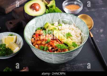 Chili con Carne und Couscous in einer Schüssel auf dunklem Hintergrund. Mexikanische Küche. Stockfoto