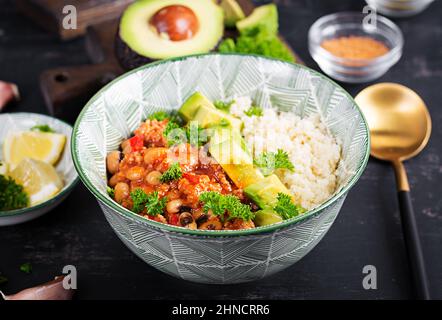 Chili con Carne und Couscous in einer Schüssel auf dunklem Hintergrund. Mexikanische Küche. Stockfoto