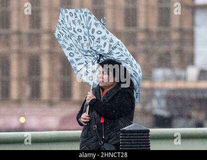 Frauen kämpfen bei nassem und windigem Wetter im Zentrum Londons mit Regenschirmen Stockfoto