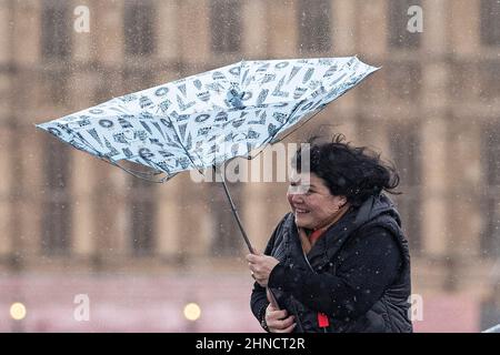 Frauen kämpfen bei nassem und windigem Wetter im Zentrum Londons mit Regenschirmen Stockfoto