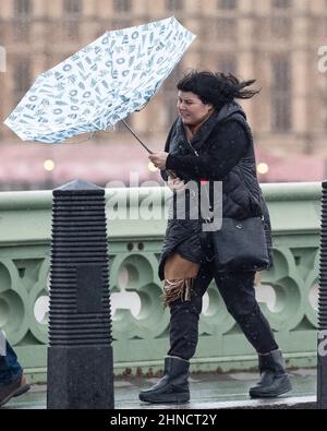 Frauen kämpfen bei nassem und windigem Wetter im Zentrum Londons mit Regenschirmen Stockfoto