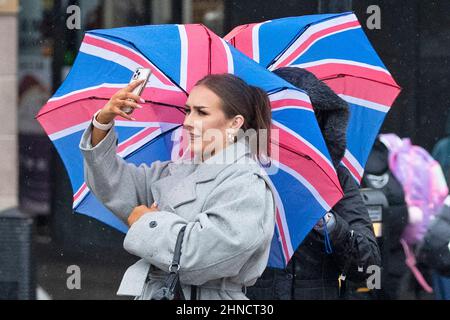 Frauen kämpfen bei nassem und windigem Wetter im Zentrum Londons mit Regenschirmen Stockfoto