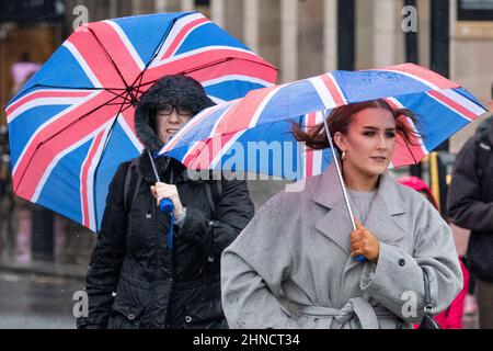 Frauen kämpfen bei nassem und windigem Wetter im Zentrum Londons mit Regenschirmen Stockfoto