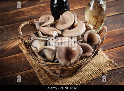 Korb mit köstlichen Bio-Austernpilzen auf Holzgrund. Stockfoto