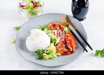 Salat mit Tomaten und Burrata-Käse mit Salat und Olivenöl auf hellem Hintergrund. Italienische Küche. Stockfoto