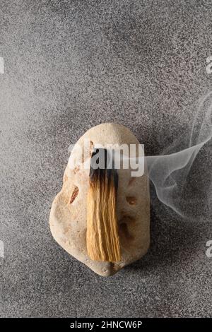 Palo Santo Räucherstäbchen, die auf Stein brennen. Heiliges Holz Rauch. Spirituelle Praktiken. Vertikales Format. Blick von oben. Stockfoto