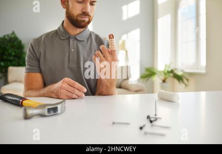 Der junge Mann muss eine Stütze am Finger tragen, nachdem er sie mit einem Hammer verletzt hat Stockfoto