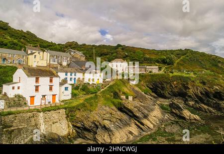 Die Häuser von Portloe auf den Klippen mit Blick auf den Hafen und die Bucht bei Ebbe. Portloe ist ein traditionelles kornisches Fischerdorf Stockfoto