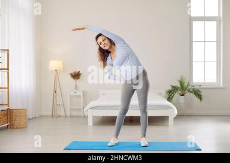 Lächelnde, gesunde Frau macht während der Schwangerschaft Gymnastik Stockfoto