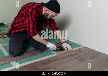 Werkmann installiert Laminat. Reparatur der Wohnung, Verlegung Laminatboden Stockfoto