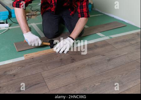 Werkmann installiert Laminat. Reparatur der Wohnung, Verlegung Laminatboden Stockfoto